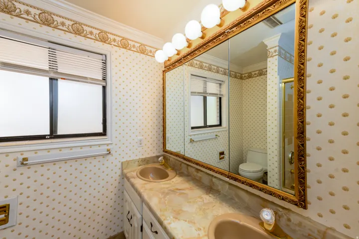 Dual vanity with integrated sinks, framed mirror, and a window for natural light