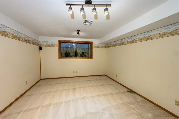 Carpeted interior with wood-trimmed window, track lighting, and decorative wall border