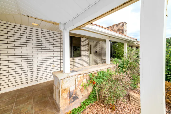 Covered front porch featuring a white brick facade and stone accent wall
