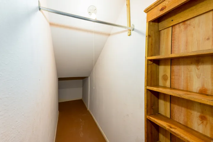 Built-in wood shelving, hanging rod, and sloped ceiling