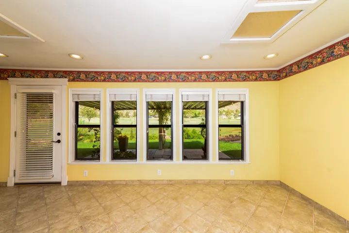 Tile flooring, recessed ceiling lighting, multiple windows, and a white door with integrated blinds