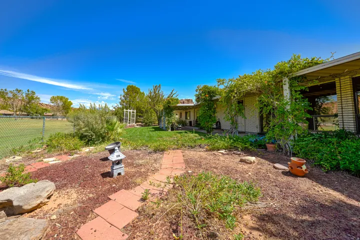 Expansive outdoor space featuring a paved pathway, mature landscaping, and a chain-link fence