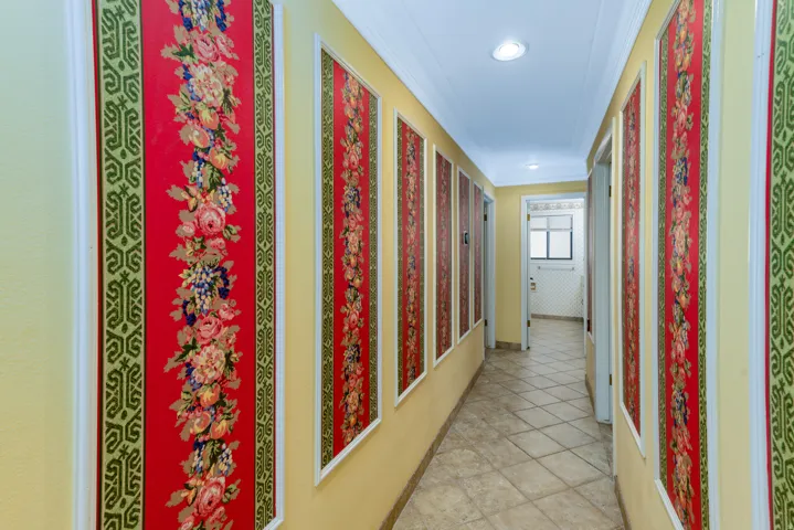 Hallway featuring decorative wall panels, recessed lighting, crown molding, and tiled flooring