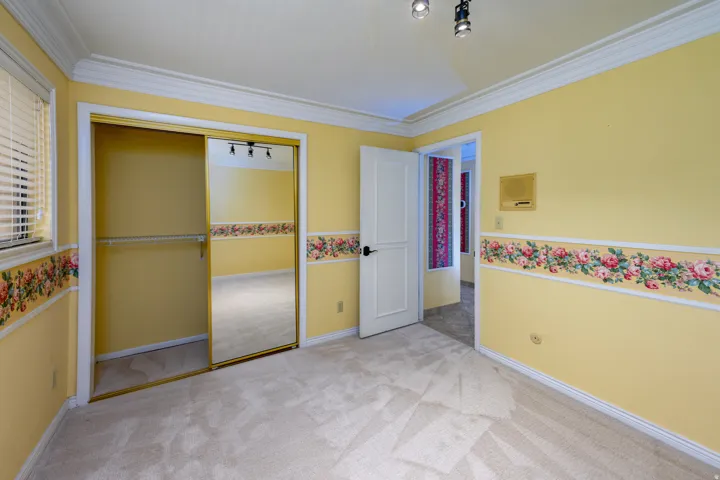 Carpeted interior with crown molding, track lighting, a mirrored closet door, and a white paneled door
