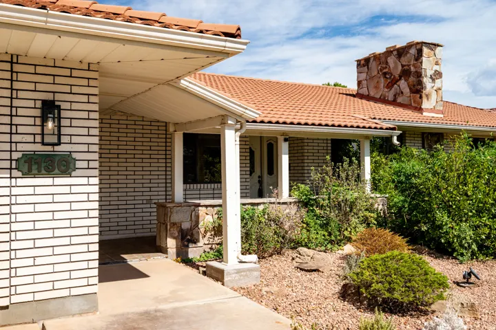White brick exterior with a terracotta tile roof and stone chimney