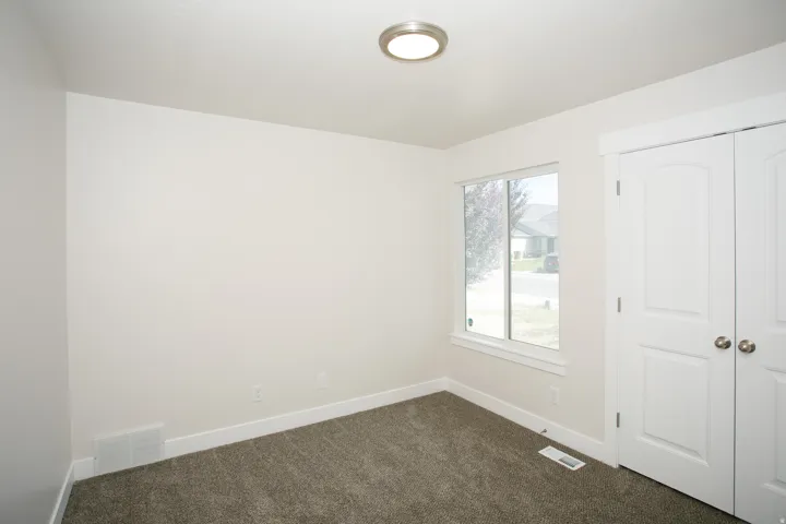 Neutral wall finishes with white trim, a double-door closet, modern flush-mount lighting, and carpeted flooring