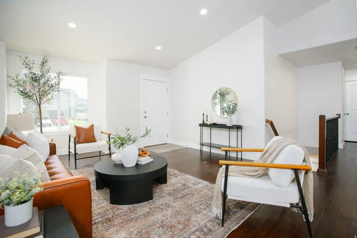 Bright living space with wood-finish flooring, recessed lighting, and a white entrance door