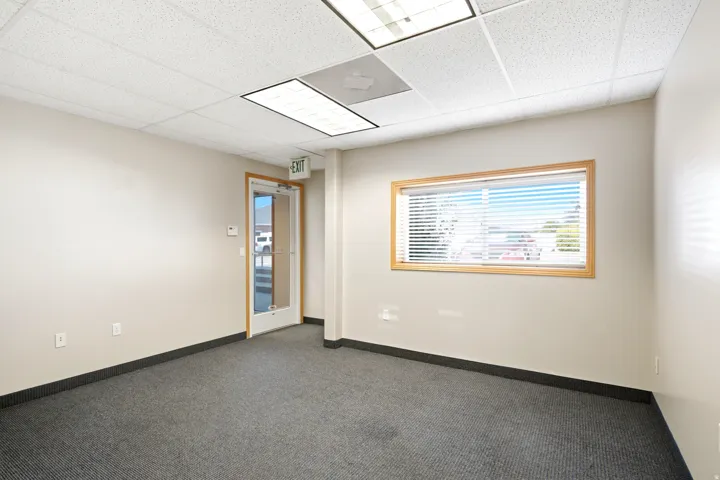 Commercial space featuring a drop ceiling, fluorescent lighting, neutral wall paint, and gray carpet