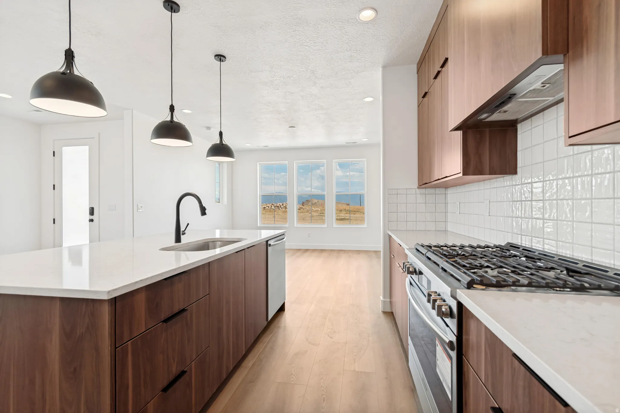 Kitchen featuring wood-finish cabinetry, 3 cm quartz countertops, a gas range, and a subway tile backsplash