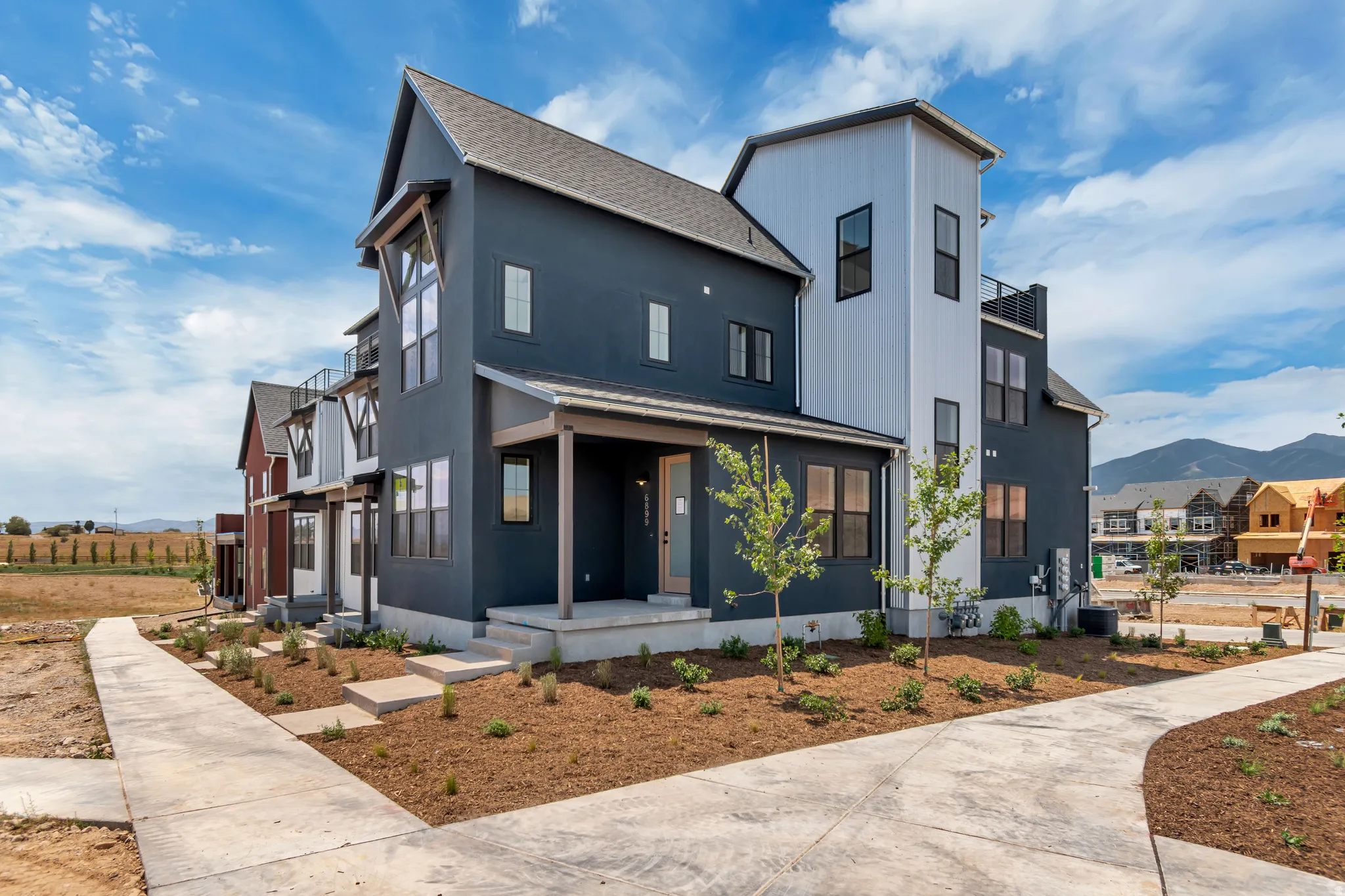 Modern farmhouse design showcasing a striking two-story exterior with contrasting dark and light architectural panels, pitched roofline with gabled details, and a covered front porch