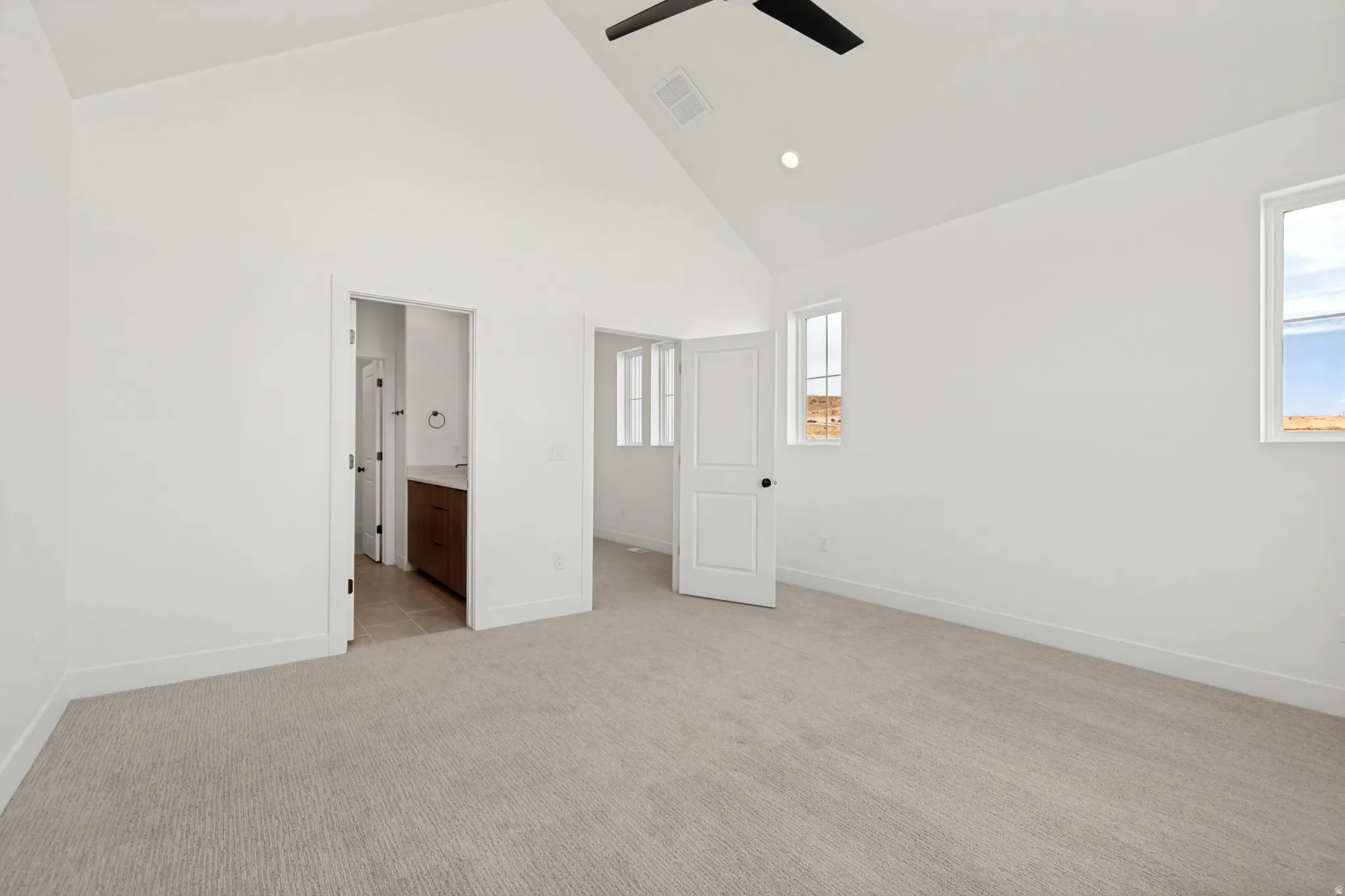 Vaulted ceiling, recessed lighting, ceiling fan, carpeted flooring, and multiple windows