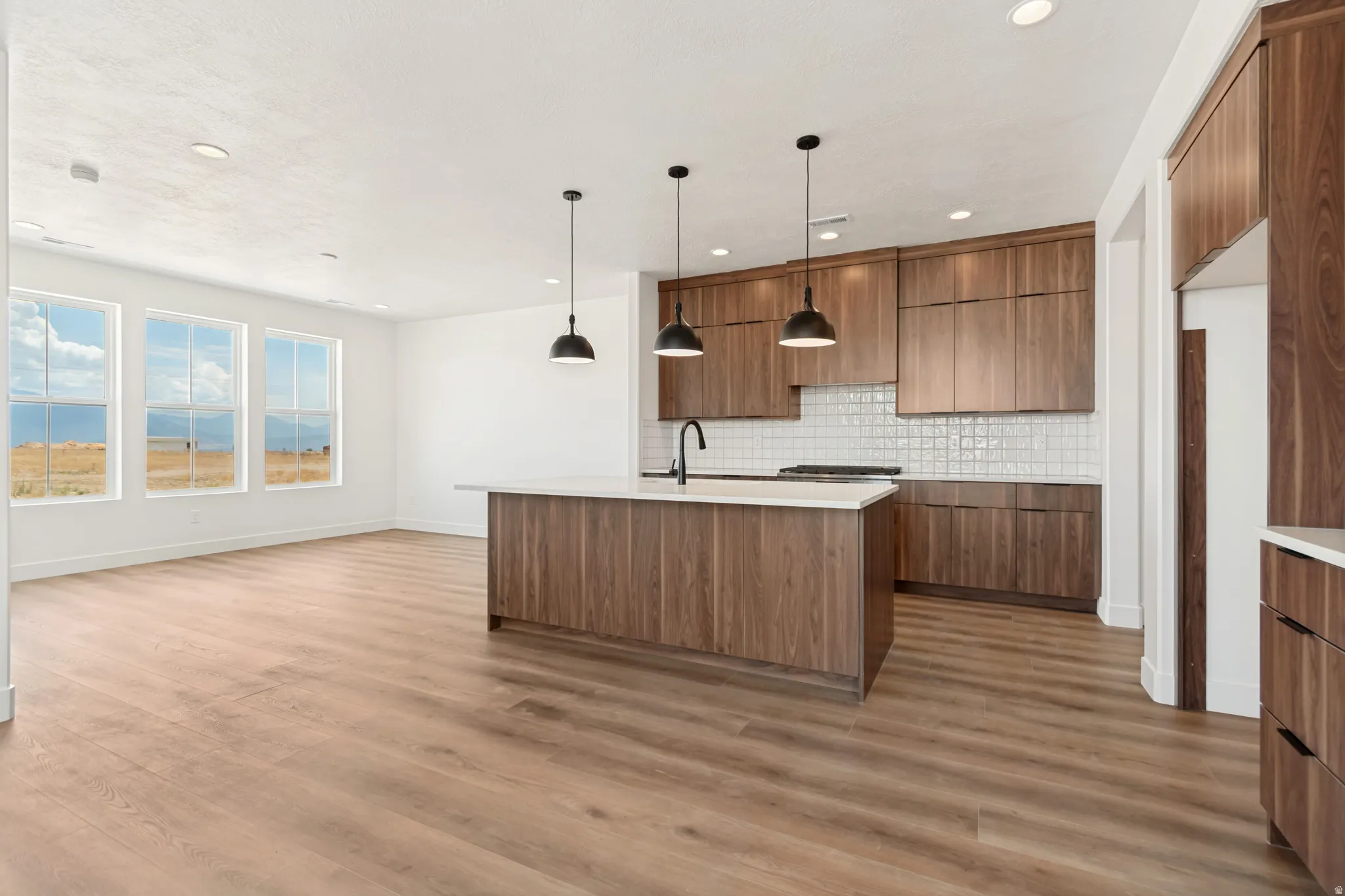 Open-concept living area featuring wood-finish flooring, a kitchen island with a white countertop, and recessed lighting