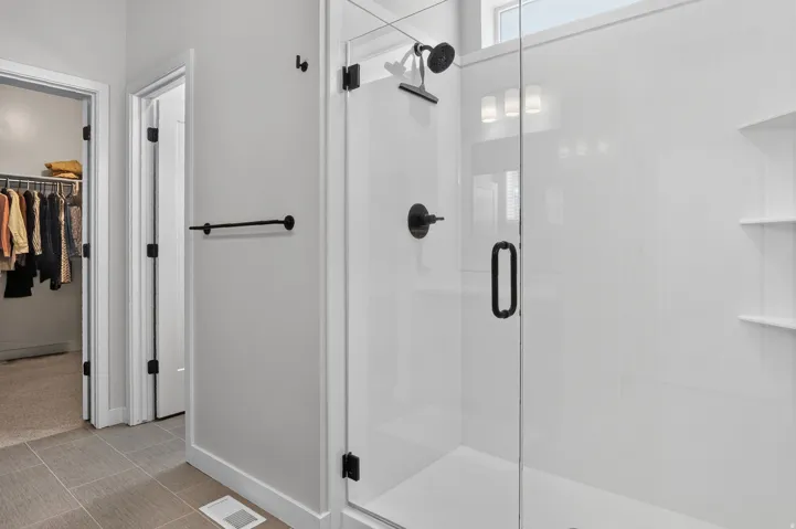 Glass-enclosed shower with matte black fixtures and built-in shelving