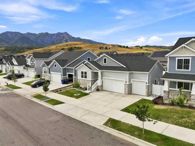 Modern residential street with homes featuring stone accents, attached garages, and manicured lawns