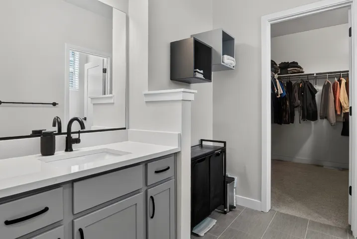 Vanity with a white countertop and gray cabinetry, matte black faucet, and a large wall mirror