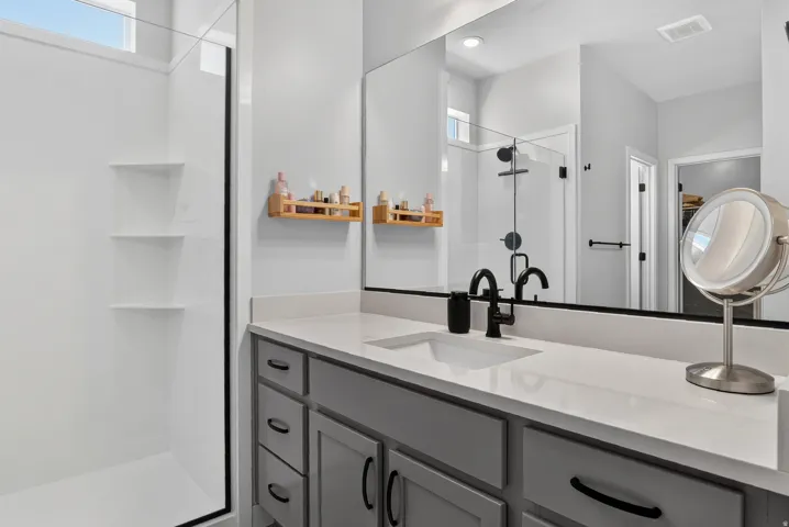White shower enclosure with built-in shelving, glass shower door, and transom window