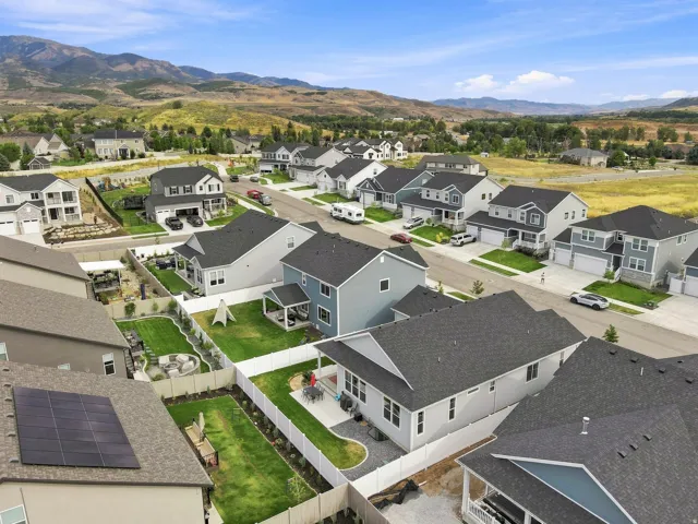 Residential development with mountain backdrop, featuring a variety of home styles, green landscaping, and paved streets