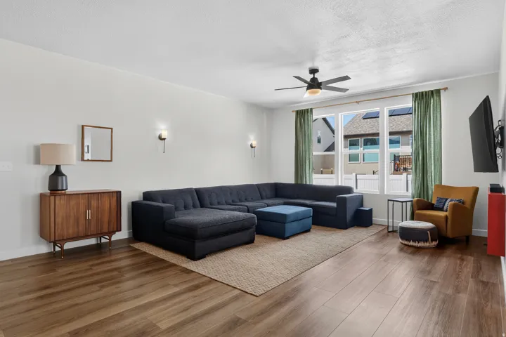 Recessed wall sconces, ceiling fan with integrated lighting, wood-finish flooring, and large picture windows