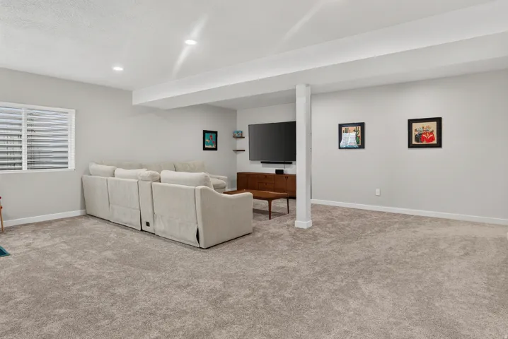 Spacious room with recessed lighting, light gray walls, plush carpet, and a window with horizontal blinds