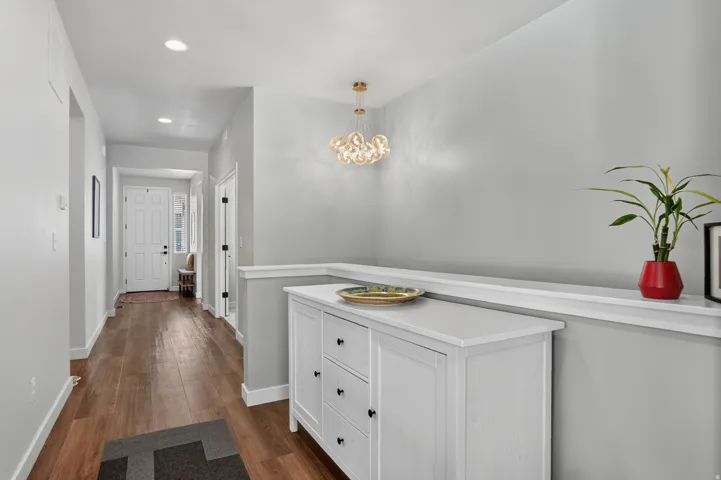Hallway featuring recessed lighting, wood-finish flooring, a contemporary chandelier, and a built-in display ledge