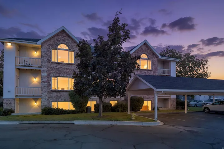 Brick and stucco exterior with arched windows, multiple balconies, a covered parking structure, and exterior lighting fixtures