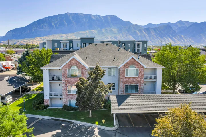 Brick and stucco exterior, multiple covered parking structures, balconies, asphalt shingle roofing, and landscaped grounds