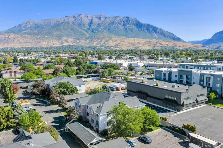 Mountain backdrop, established neighborhood, multi-story residential buildings, commercial structures, and surface parking