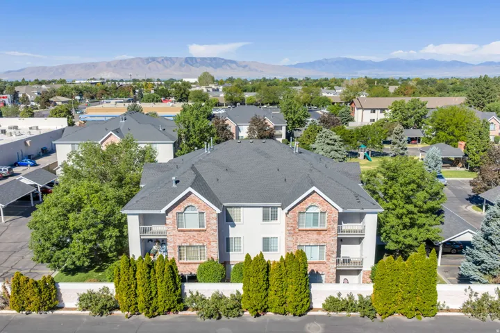Stucco and brick exterior with multiple balconies, covered parking, and landscaping