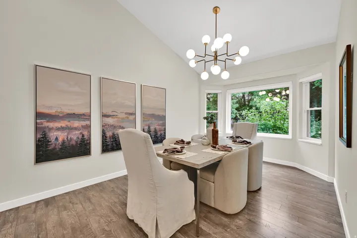 Vaulted ceiling with a modern chandelier, wood-finish flooring, and a bay window
