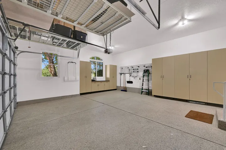 Epoxy-coated flooring, built-in storage cabinetry, overhead storage, and grid storage wall rack