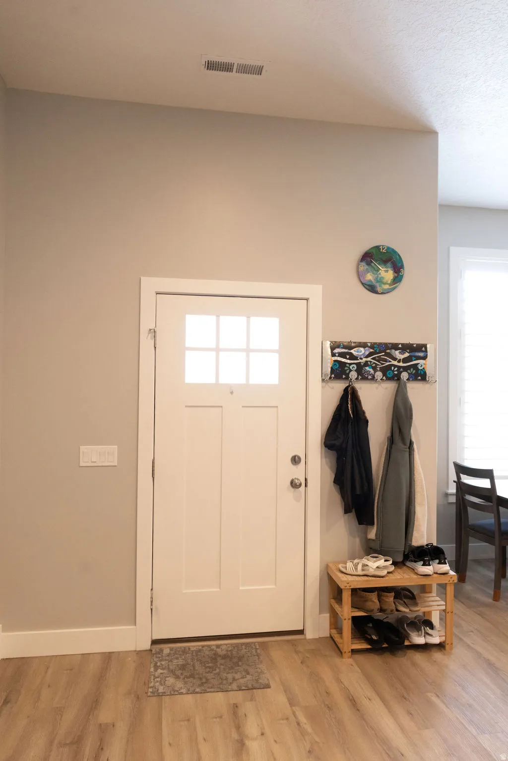 Entryway featuring a white door with upper window panes, wood-finish flooring, and white trim