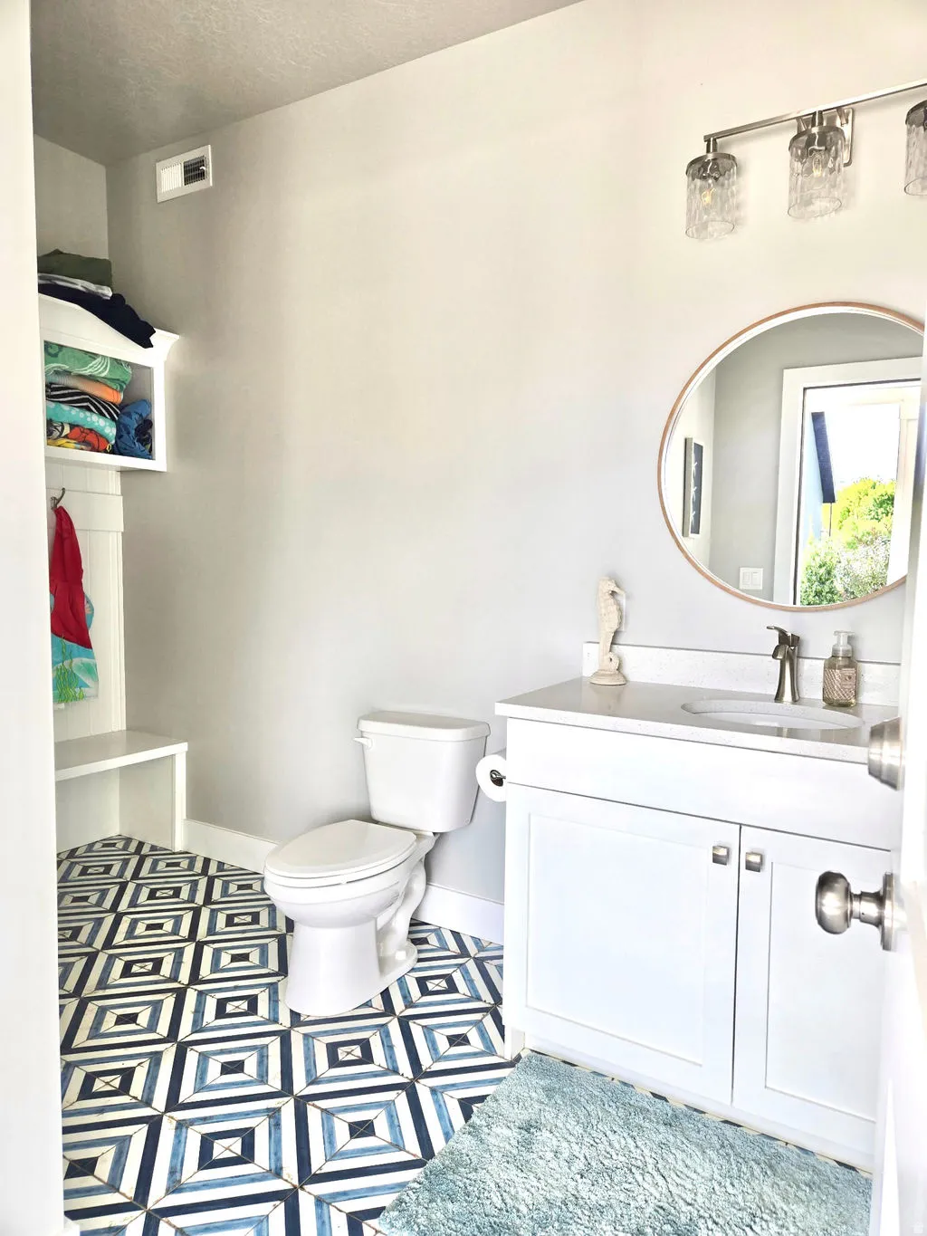 White vanity with a single basin, brushed nickel faucet, and a circular mirror