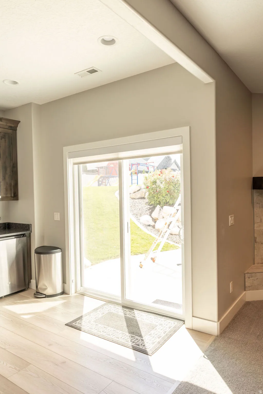 Sliding glass door, recessed lighting, wood-finish flooring, stone fireplace surround, dark wood cabinetry