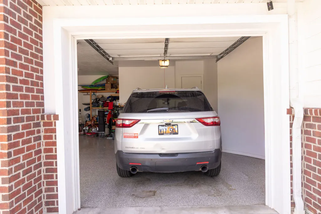 Attached garage with brick exterior, overhead lighting, and an epoxy-coated concrete floor