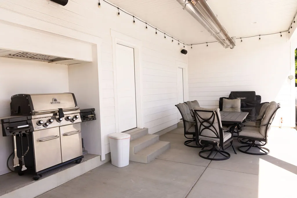 Covered patio featuring an outdoor kitchen area with a built-in exhaust hood, string lighting, and a ceiling-mounted heater