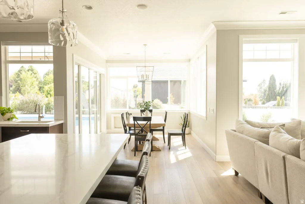 Open-concept living space with light wood-finish flooring, a kitchen island featuring a light-toned countertop, and multiple large windows