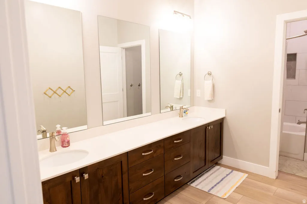 Dual vanity with undermount sinks, wood-finish cabinetry, and light-toned countertops