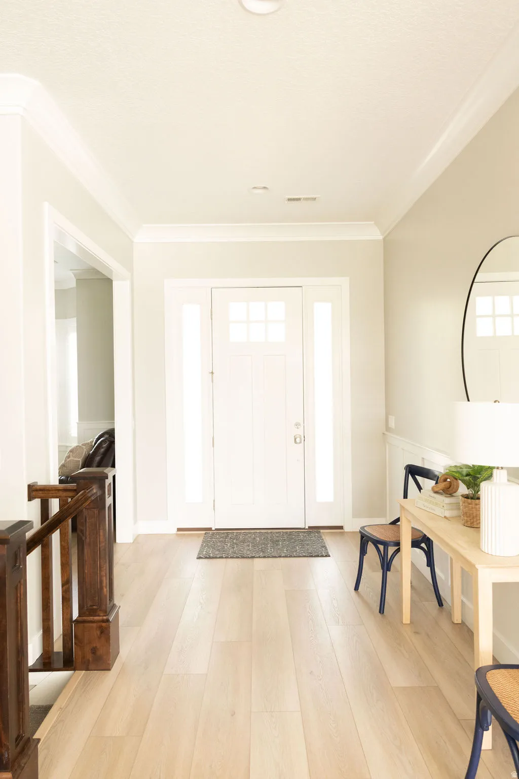 Entryway featuring wood-finish flooring, a white paneled front door with sidelights, and crown molding
