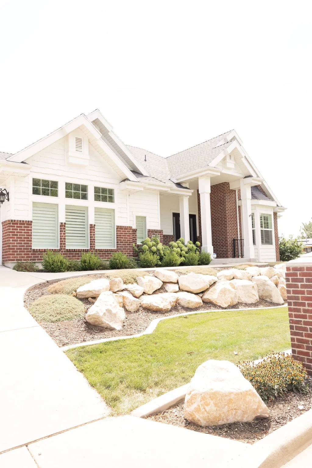 Exterior featuring white siding, brick accents, and a covered entry with columns