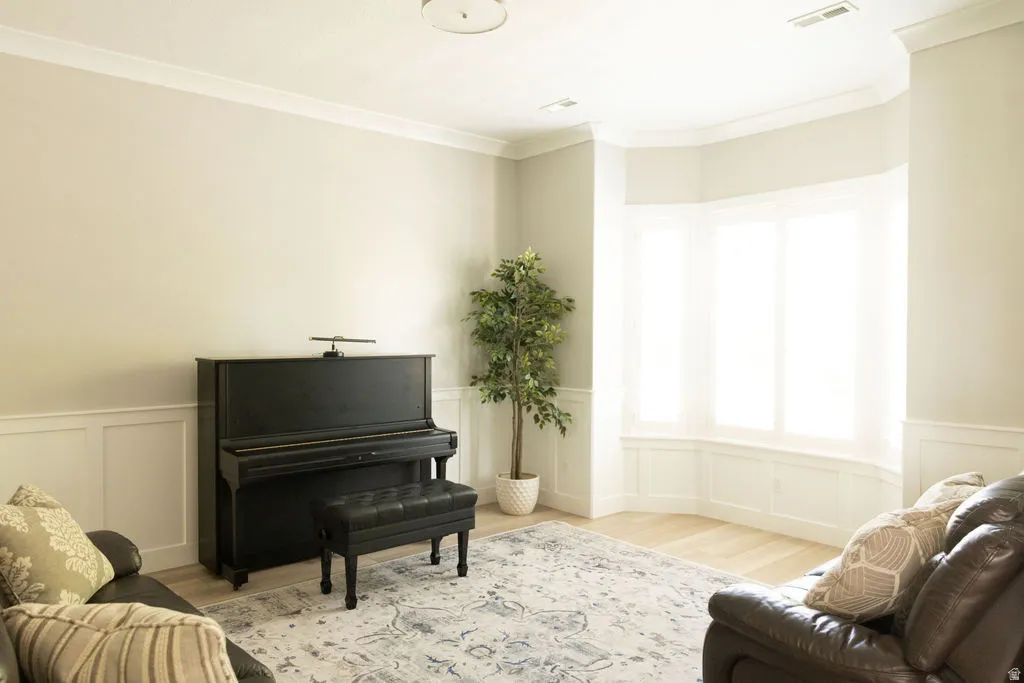 Crown molding accents, wainscoting details, bay window with integrated seating, and light wood-finish flooring