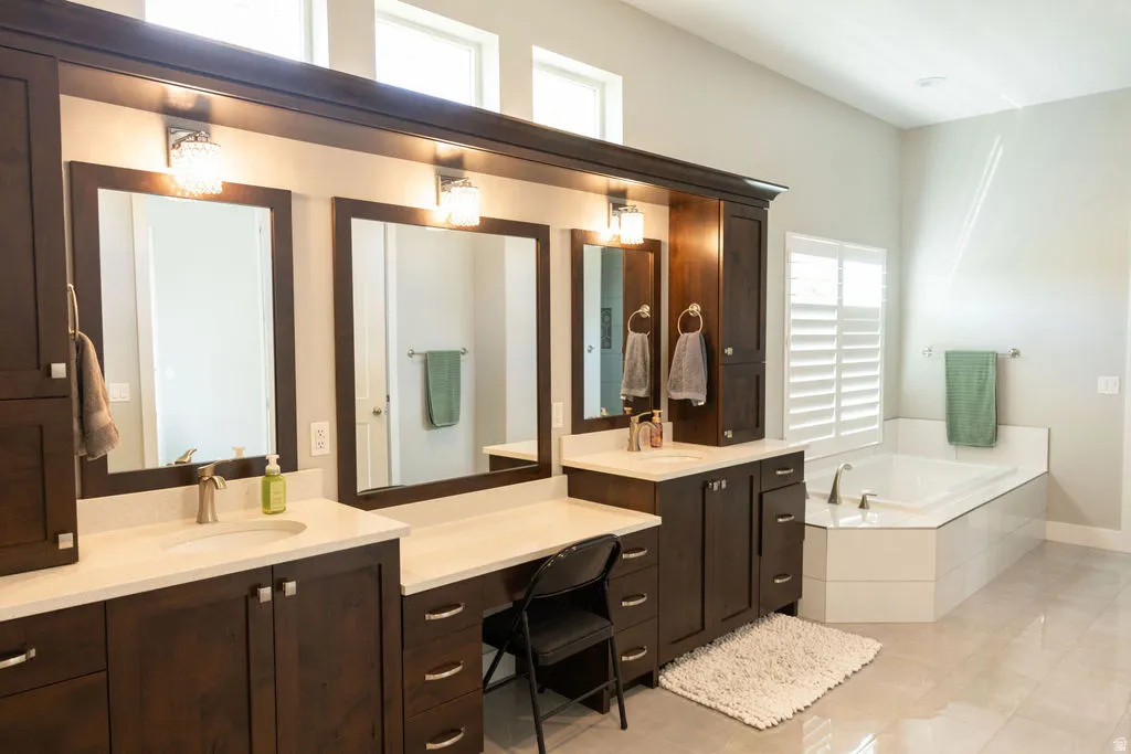 Double vanities with integrated sinks, ample cabinetry storage, a built-in vanity station, and a corner soaking tub