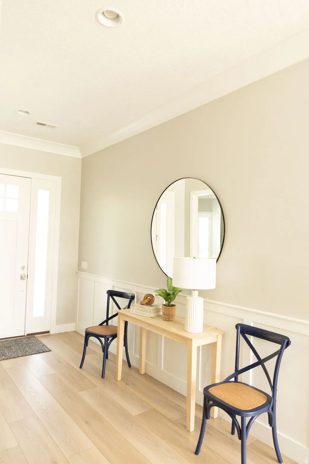 Light wood-finish flooring with white wainscoting and crown molding