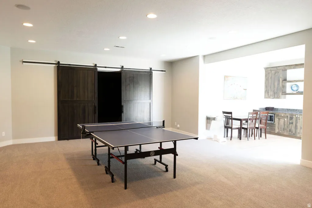 Spacious carpeted room featuring recessed lighting and a built-in wet bar with cabinetry