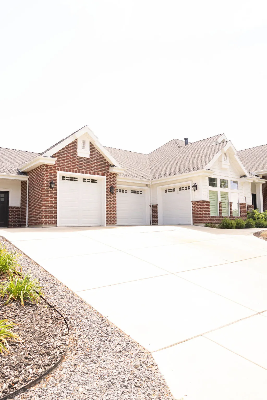 Exterior featuring brick and siding finishes, multiple garage doors, and a concrete driveway