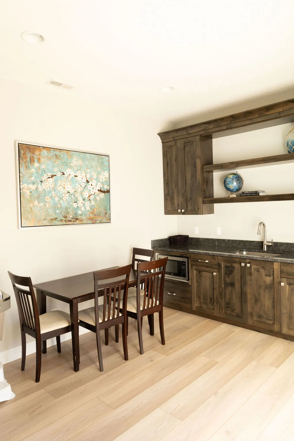Wood-finish flooring, recessed lighting, built-in cabinetry, dark countertop, and an integrated sink