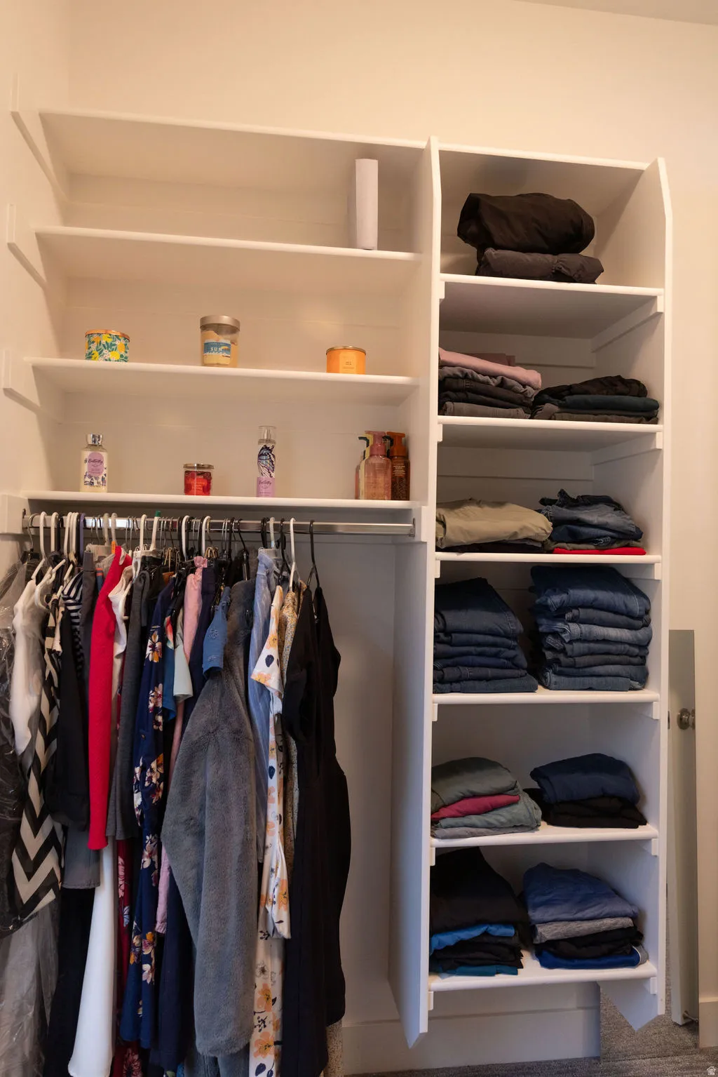 Built-in white storage system featuring multiple shelves and a hanging rod