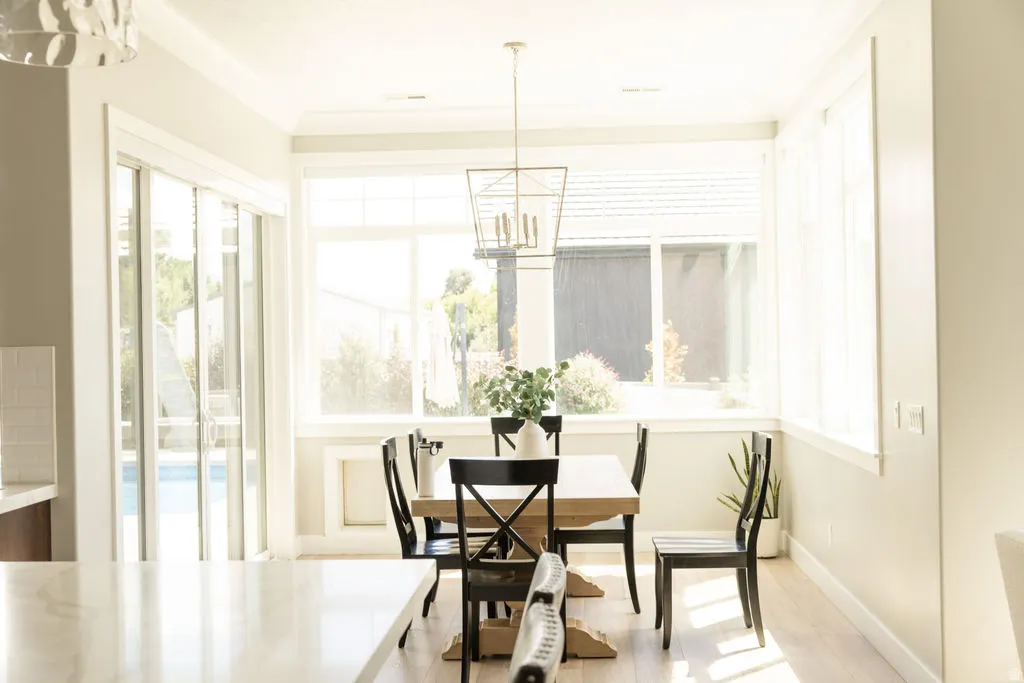 Dining area with large windows, wood-finish flooring, and a contemporary light fixture