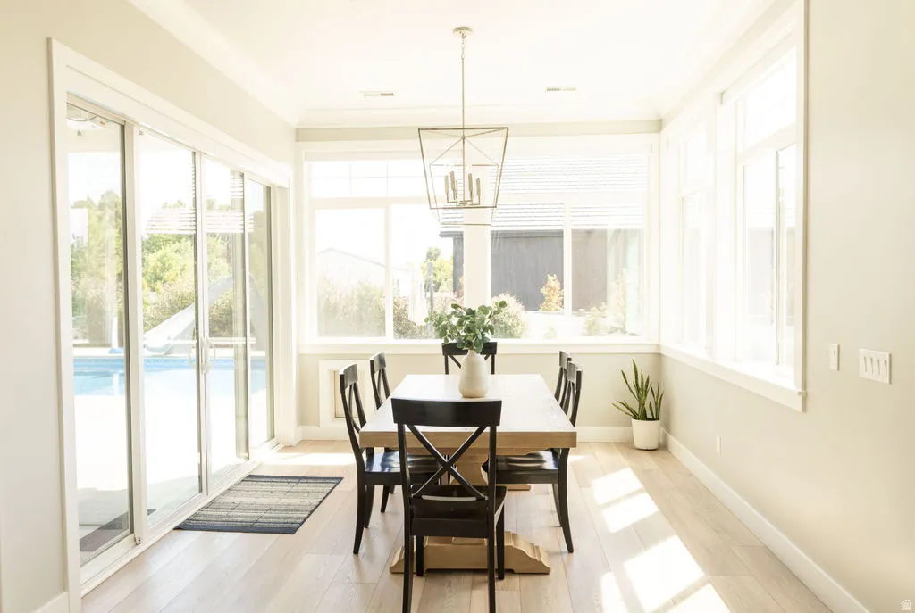 Dining area featuring wood-finish flooring, a contemporary geometric chandelier, and multiple windows