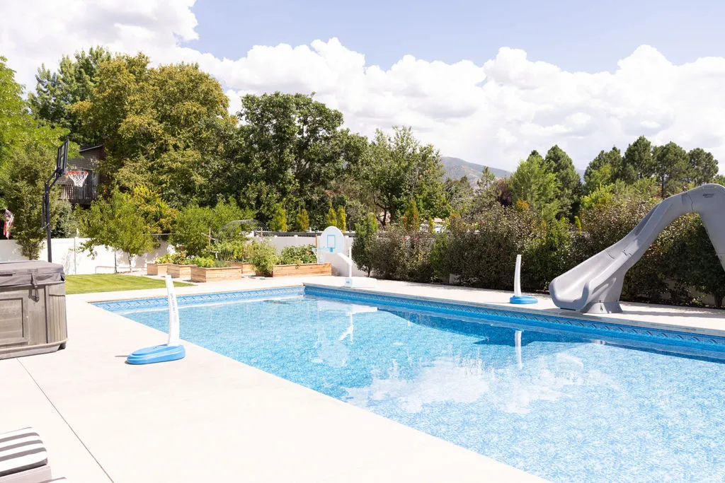 Expansive backyard featuring an in-ground swimming pool, concrete patio, spa, and raised garden beds