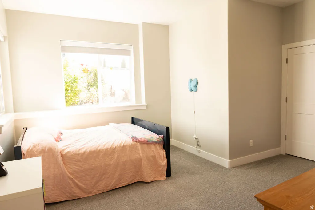 Light-filled room featuring a large window, neutral wall paint, and gray carpet flooring
